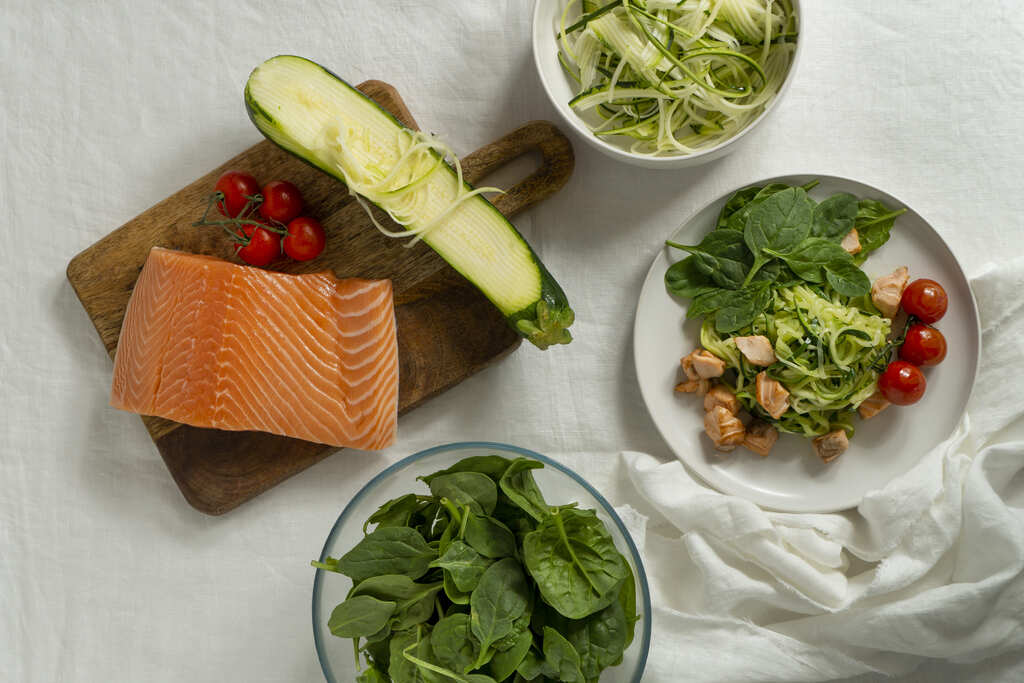 Mesa con ingredientes naturales, pasta, salmón y espinacas