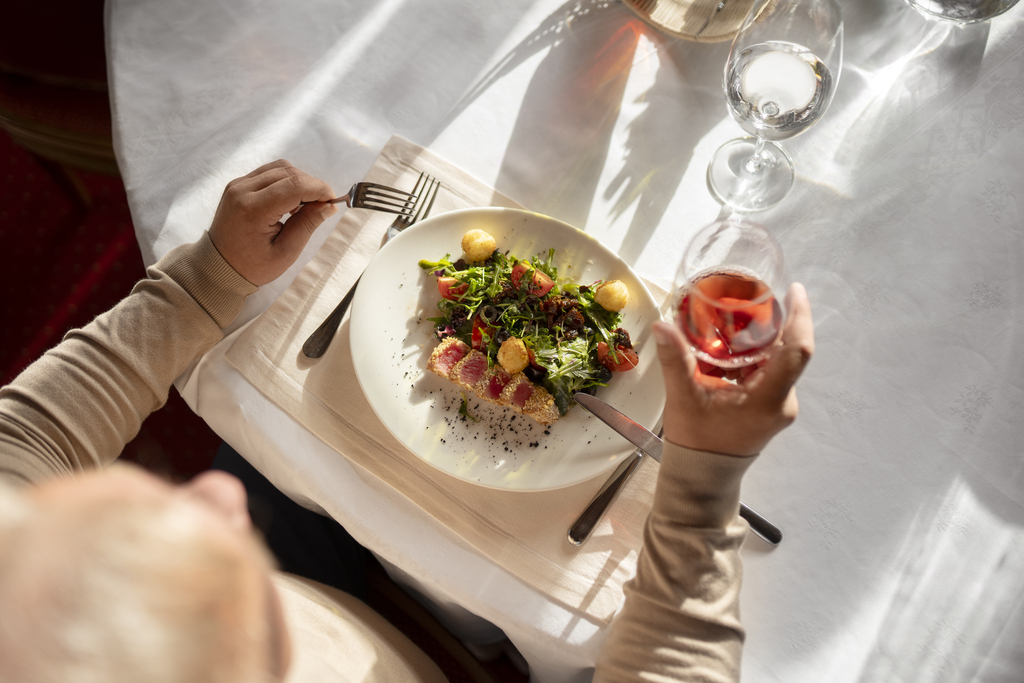 Comensal en restaurante con una copa y un plato de tataki